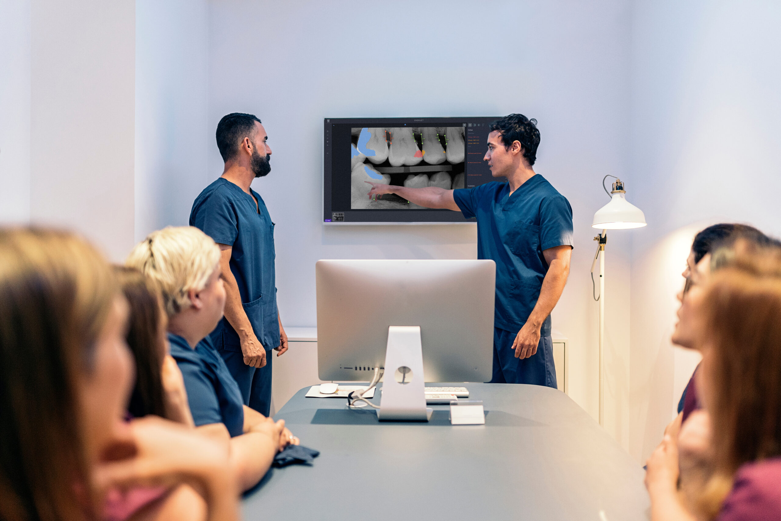 Dentists and clinical team members look at Overjet on a monitor.